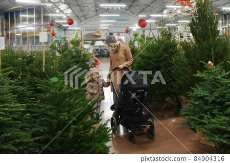 Mother and daughter choose a Christmas tree in a shop 84904316