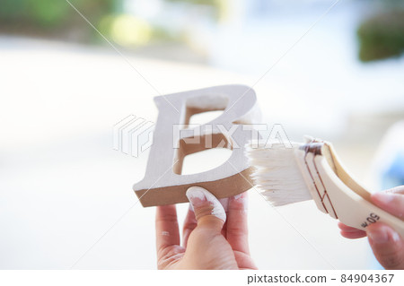 DIY to paint the alphabet with white paint at the hands of a woman DIY to paint the alphabet with white paint at the hands of a woman 84904367