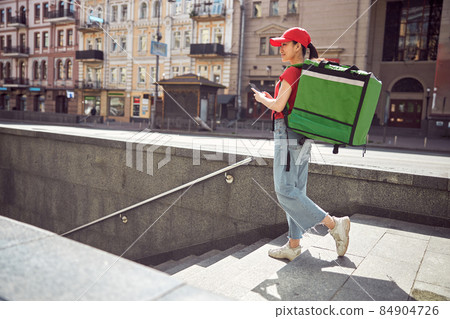 Delivery service worker carrying food order on city street 84904726