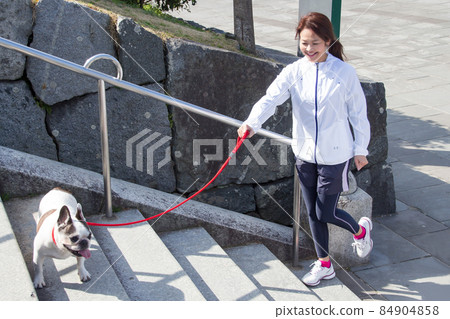 A woman walking the stairs with a dog 84904858
