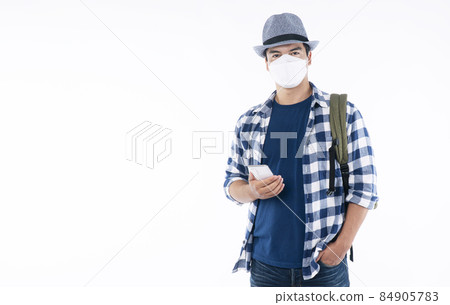Traveler young man wear shirt, hat and face mask with backpack protect outbreak holding smartphone Traveler young man wear shirt, hat and face mask with backpack protect outbreak holding smartphone 84905783