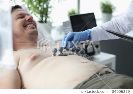Cardiologist put electrocardiogram equipment on patient chest and do cardiogram test 84906259