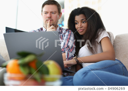 Middle aged man and latino american woman watch impressive film online 84906269
