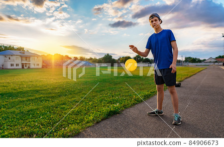 teen boy playing with a ball at a stadium, a soccer field with green grass - sports and health concept 84906673