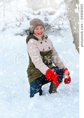a girl plays snowballs outside, beautiful winter weather and white snow around 84906985