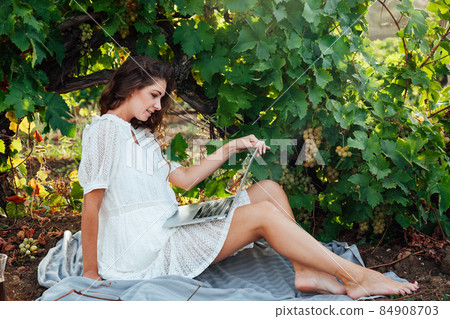 woman working on a laptop online in a vineyard 84908703
