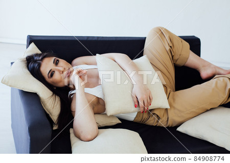 fashionable oriental brunette woman on a black sofa fashionable oriental brunette woman on a black sofa 84908774
