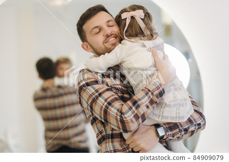 Adorable daughter with her dear father at home in gront of fit tree. Chrisrmas mood. Daughter hug father Adorable daughter with her dear father at home in gront of fit tree. Chrisrmas mood. Daughter hug father 84909079