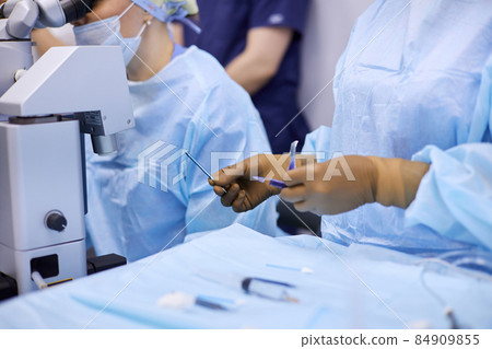 Surgeons performing eye surgery in the operating room 84909855