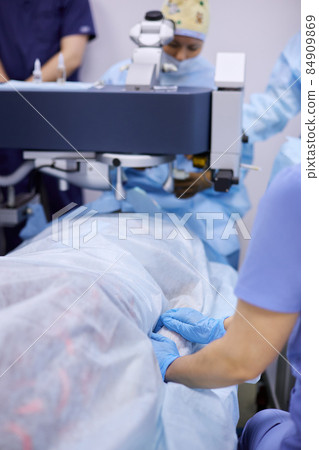 Surgeons performing eye surgery in the operating room 84909869