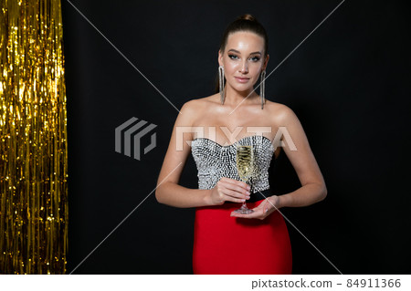 portrait of a beautiful fashionable woman in a festive dress with a glass of wine at a party 84911366