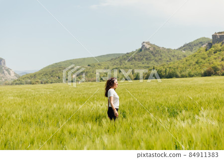 woman tourist walking through a field of wheat on a journey woman tourist walking through a field of wheat on a journey 84911383