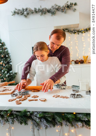 Father with daughter cooking making gingerbread, cutting cookies of gingerbread dough, having fun. Father with daughter cooking making gingerbread, cutting cookies of gingerbread dough, having fun. 84914477