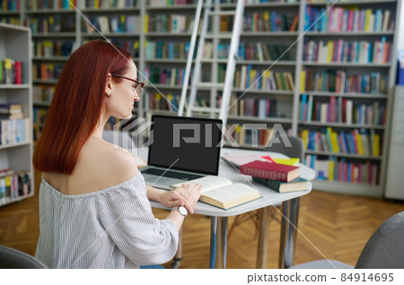 Back view of woman reading book in library Back view of woman reading book in library 84914695