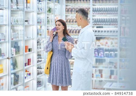 Male pharmacist consulting a customer in a drugstore 84914738