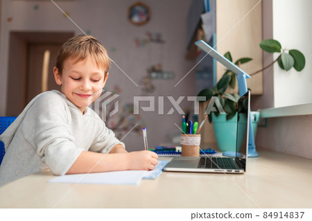 Cute little schoolboy studying at home doing school homework. Distance learning online education Cute little schoolboy studying at home doing school homework. Distance learning online education 84914837