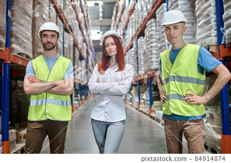 Woman and two men in warehouse looking at camera 84914874