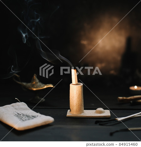 Palo Santo stick on fire with smoke in a beautiful candlestick. Cozy evening at home. 84915460