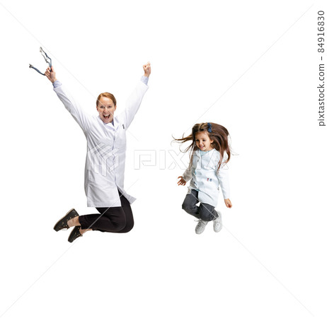 Portrait of cute beautiful little girl, child in image of nurse and female doctor jumping isolated on white studio background 84916830