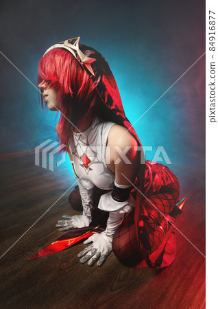 Cosplay. Studio portrait of attractive sexy young woman in anime rosary costume with red hairs and white gloves. Sexual pose on the floor in colored light Cosplay. Studio portrait of attractive sexy young woman in anime rosary costume with red hairs and white gloves. Sexual pose on the floor in colored light 84916877