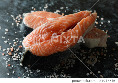 Fresh raw salmon and salt on black smokey background Fresh raw salmon and salt on black smokey background 84917716