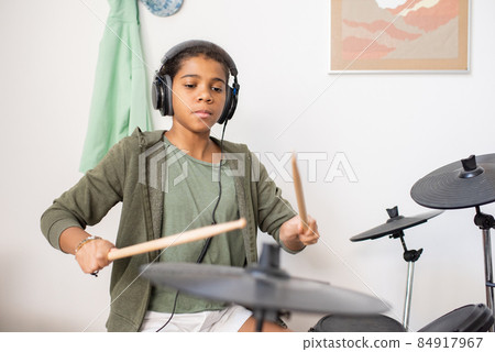 Cute schoolgirl in headphones playing drumkit Cute schoolgirl in headphones playing drumkit 84917967