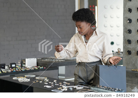 Young African consumer standing by large display with jewelry Young African consumer standing by large display with jewelry 84918249