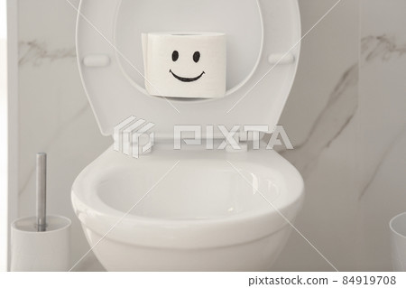 Roll of paper with funny face on toilet bowl in bathroom Roll of paper with funny face on toilet bowl in bathroom 84919708