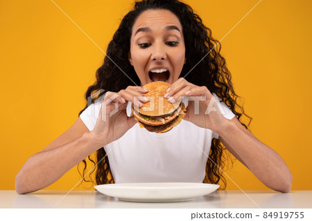 Happy Latin Lady Holding Burger Biting Sandwich At Studio Happy Latin Lady Holding Burger Biting Sandwich At Studio 84919755