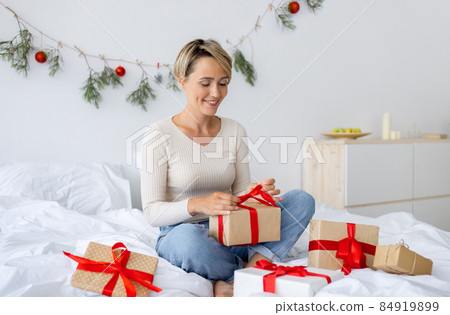 Happy lady celebrating Christmas wrapping gift box Happy lady celebrating Christmas wrapping gift box 84919899