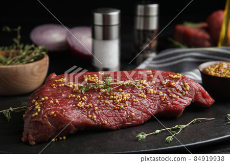 Fresh raw beef cut with thyme and mustard on table, closeup Fresh raw beef cut with thyme and mustard on table, closeup 84919938