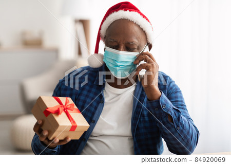 Black Man In Mask Talking On Phone Holding Gift Indoor 84920069