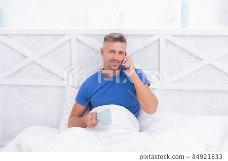 Morning call. Happy man have phone call in bed. Mobile talking. Cellular communication 84921833