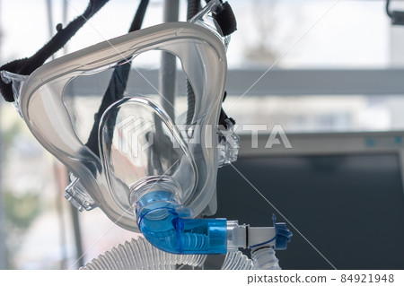 Non-invasive ventilation face mask, close up view, on background medical ventilator in ICU in hospital. 84921948