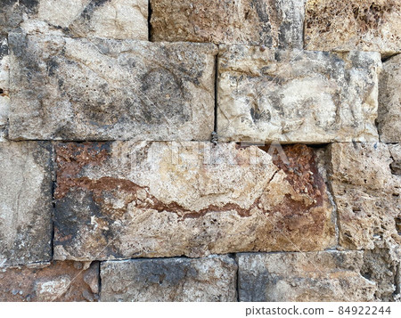 An ancient stone wall made of stones and hewn blocks 84922244