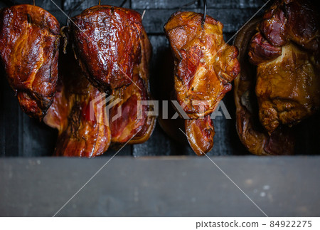Close up of smoked meat and belly or beech meat with dark crust in the smokehouse or smoker, food concept Close up of smoked meat and belly or beech meat with dark crust in the smokehouse or smoker, food concept 84922275