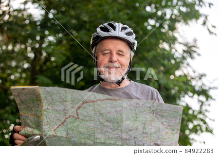 Senior man looking to the map during his bike or cycling trip in the forest, healthy lifestyle concept 84922283