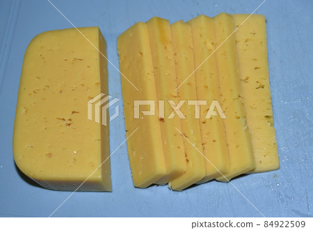 Pieces of juicy cheese cut on a cutting board 84922509