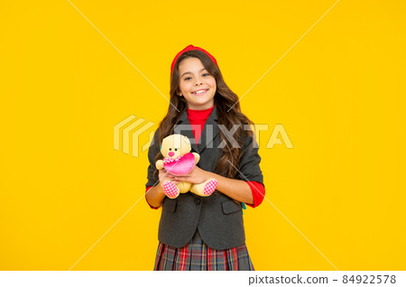 smiling teen girl in uniform holding toy on yellow background, back to school smiling teen girl in uniform holding toy on yellow background, back to school 84922578