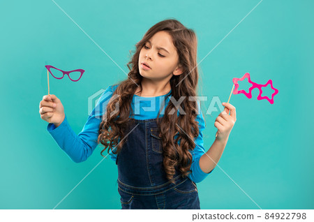 serious kid with curly hair choosing party accessory of glasses, childhood serious kid with curly hair choosing party accessory of glasses, childhood 84922798