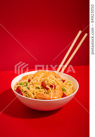 Asian noodles with shrimps in bowl, minimal red background 84923050