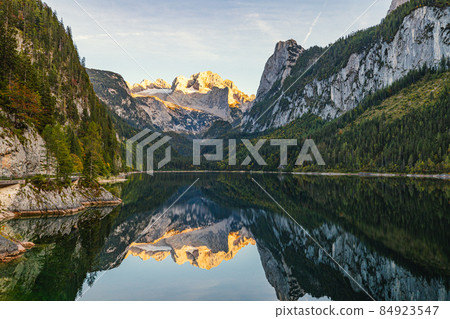 Beautiful view of idyllic colorful autumn scenery with Dachstein mountain summit reflecting in crystal clear Gosausee mountain lake in fall, Salzkammergut region, Upper Austria. Beautiful view of idyllic colorful autumn scenery with Dachstein mountain summit reflecting in crystal clear Gosausee mountain lake in fall, Salzkammergut region, Upper Austria. 84923547