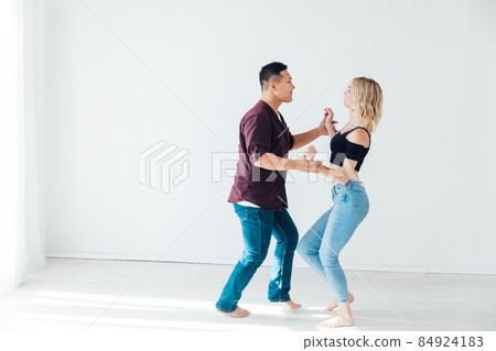 a woman and a man dancing to the music of a bachata in a white hall a woman and a man dancing to the music of a bachata in a white hall 84924183