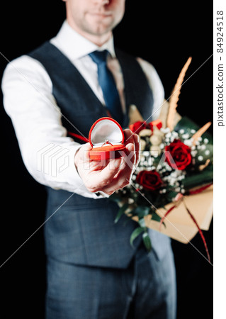 Love propose. Diamond engagement ring, red roses bouquet in young happy man hands. Marriage proposal. Marry me concept. 84924518