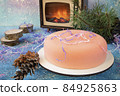 Traditional French mass Christmas cake with decoration - pine, fir cones, tinsel and serpentine with a fireplace in the background 84925863