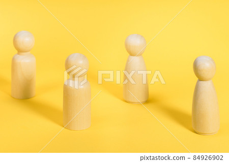 Wooden people figures stand on yellow backdrop. Society behavior, social distancing during pandemic. between people Wooden people figures stand on yellow backdrop. Society behavior, social distancing during pandemic. between people 84926902