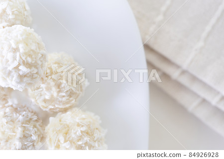 Candies in plate covered by chocolate, shredded coconut and kitchen towel on rustic wooden background. 84926928