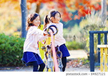 Twin girls playing in the park 84927121