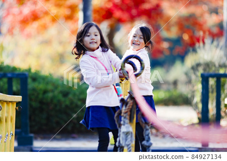 Twin girls playing in the park Twin girls playing in the park 84927134