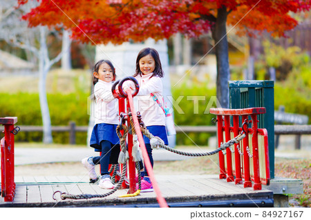 Twin girls playing in the park 84927167